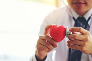 doctor holding hands with red heart in clinic office, Healthy li Doctor holding heart in hands with stethoscope